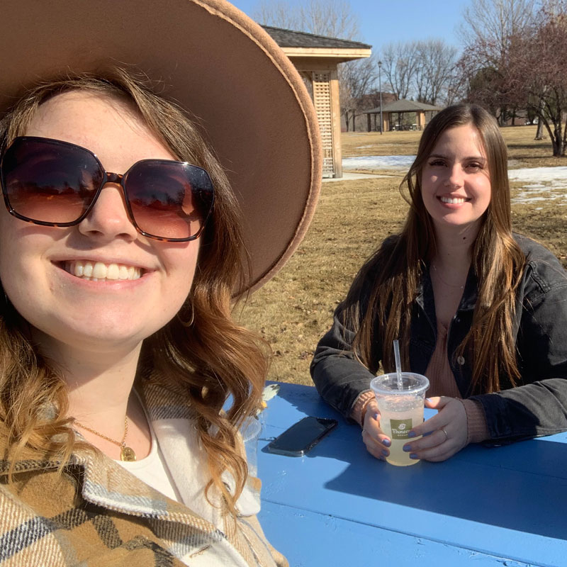 2 girls sitting at the park enjoying the nice weather and their lunch while exploring Grand Forks, ND