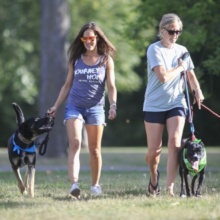 Two women walking dogs outside.