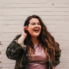 Woman laughing in front of a white brick building in Downtown Grand Forks