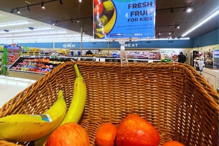 blue-zones-fruit A Blue Zones sign that reads "Fresh Fruit for Kids" is attached to a basket of fresh produce in a Grand Forks Hugo's location.