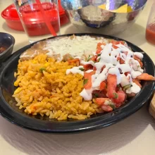 kenneth-grand-forks-cuisine-rice Black plate with rice, beans, tomato, and sour cream in Grand Forks.