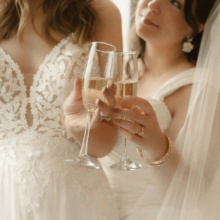 Grand Forks Wedding Two brides clink their champagne glass together on their wedding day.