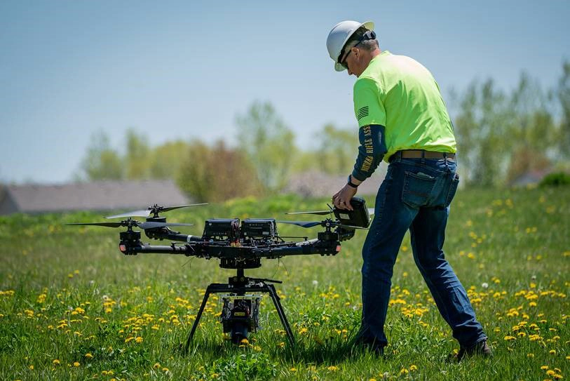 UAS-small-drone UAS small drone in a field with a man in a bright green shirt in Grand Forks.