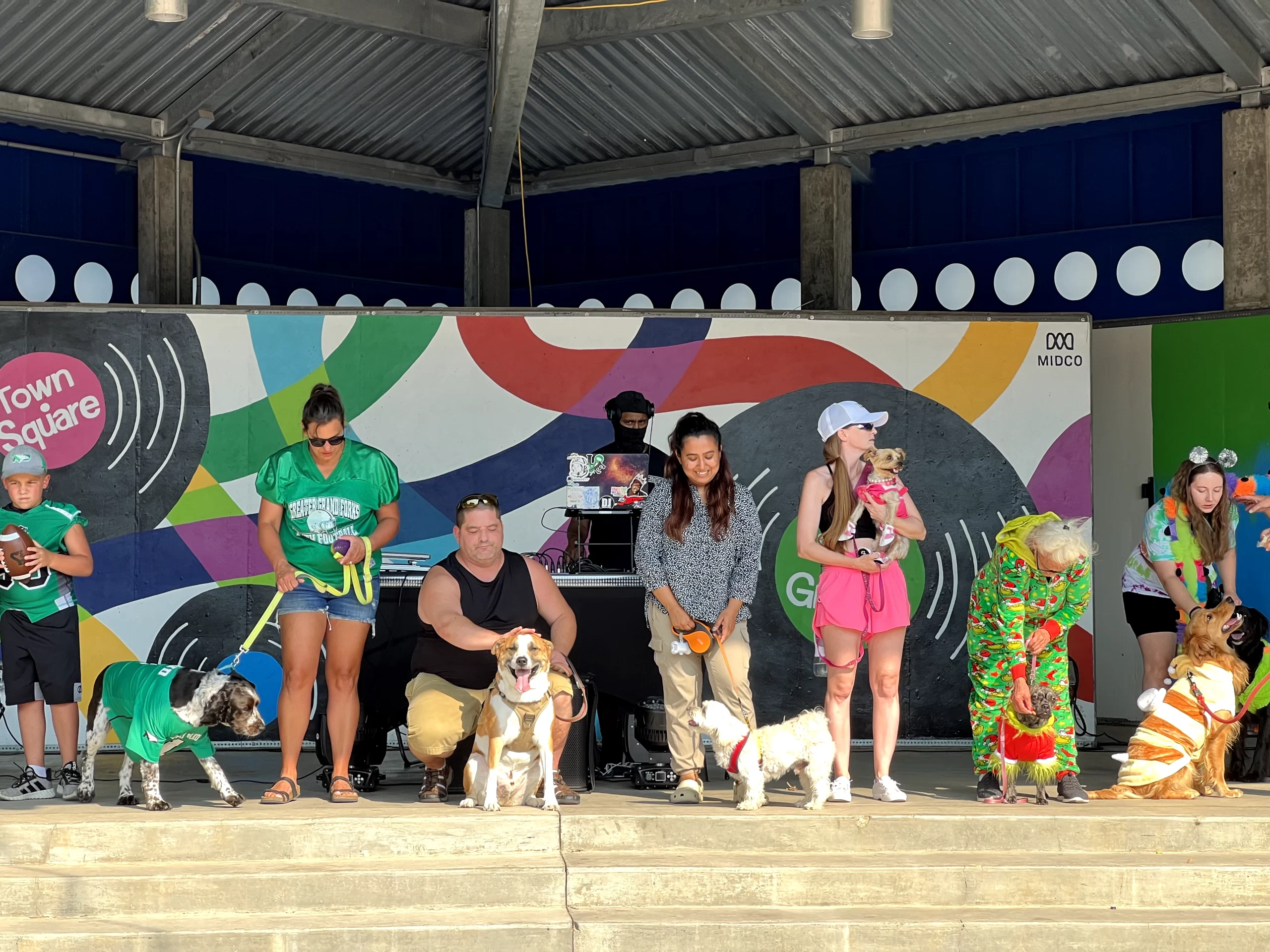puppys-in-grand-forks-town-square WCT writer Benu stands with her dog, Rio, in a line of other proud owners and their pups during the Puppy Parade at the Downtown Street Fair