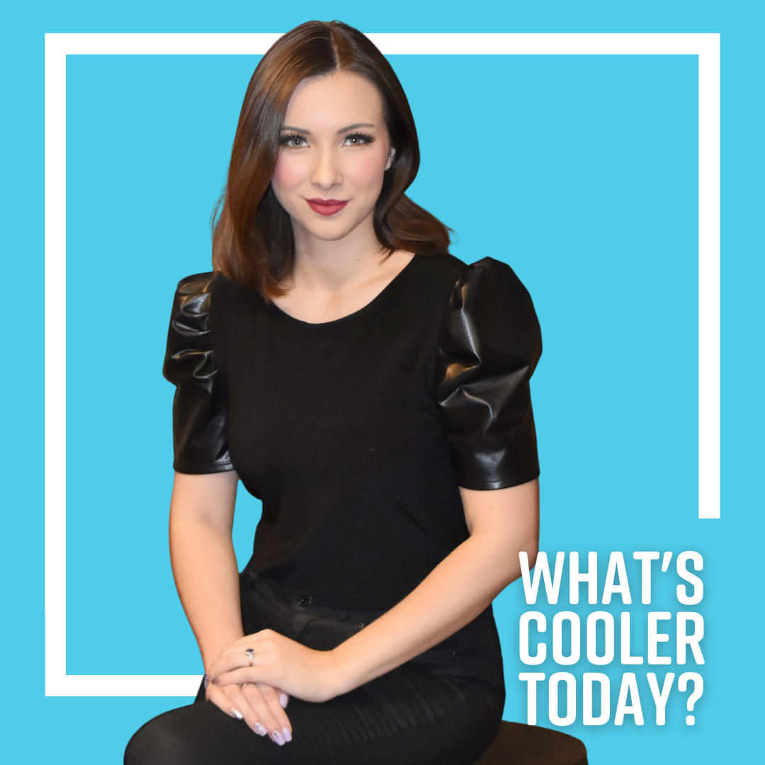 Author Klaudia sits on a stool posed for her headshot wearing all black.
