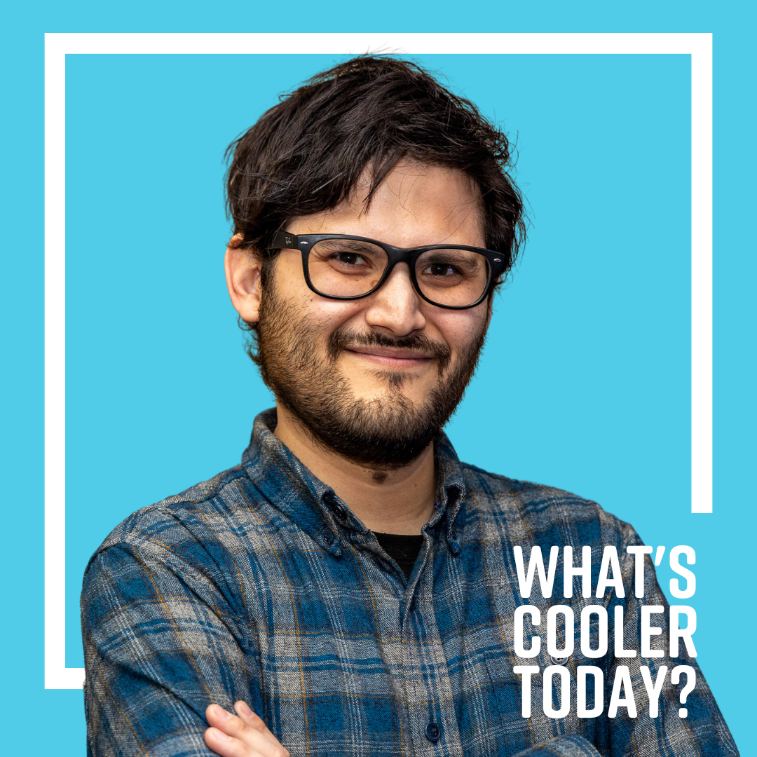 Author Adrian poses for a headshot wearing a blue and grey flannel and a smile on his face