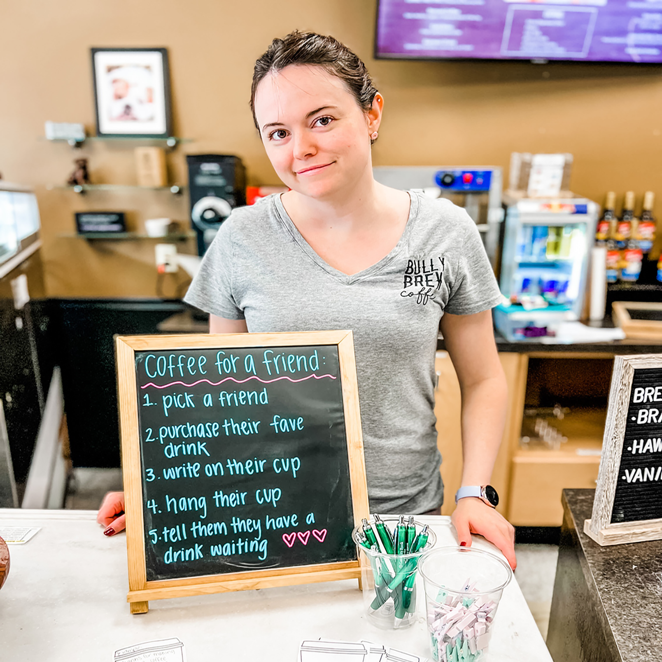 Bully Brew Employee poses with their sign that describes their pay it forward movement.