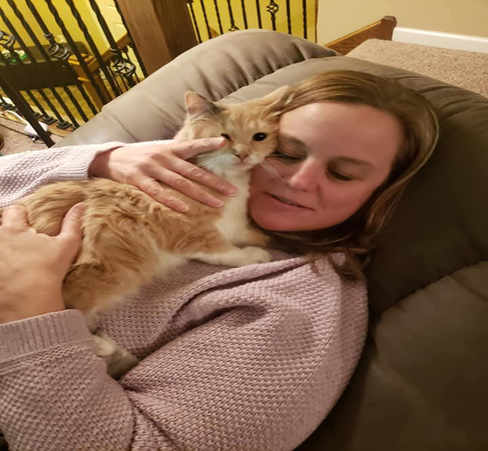 Author Dave's wife Jen holds their kitty on their couch for a snuggle.