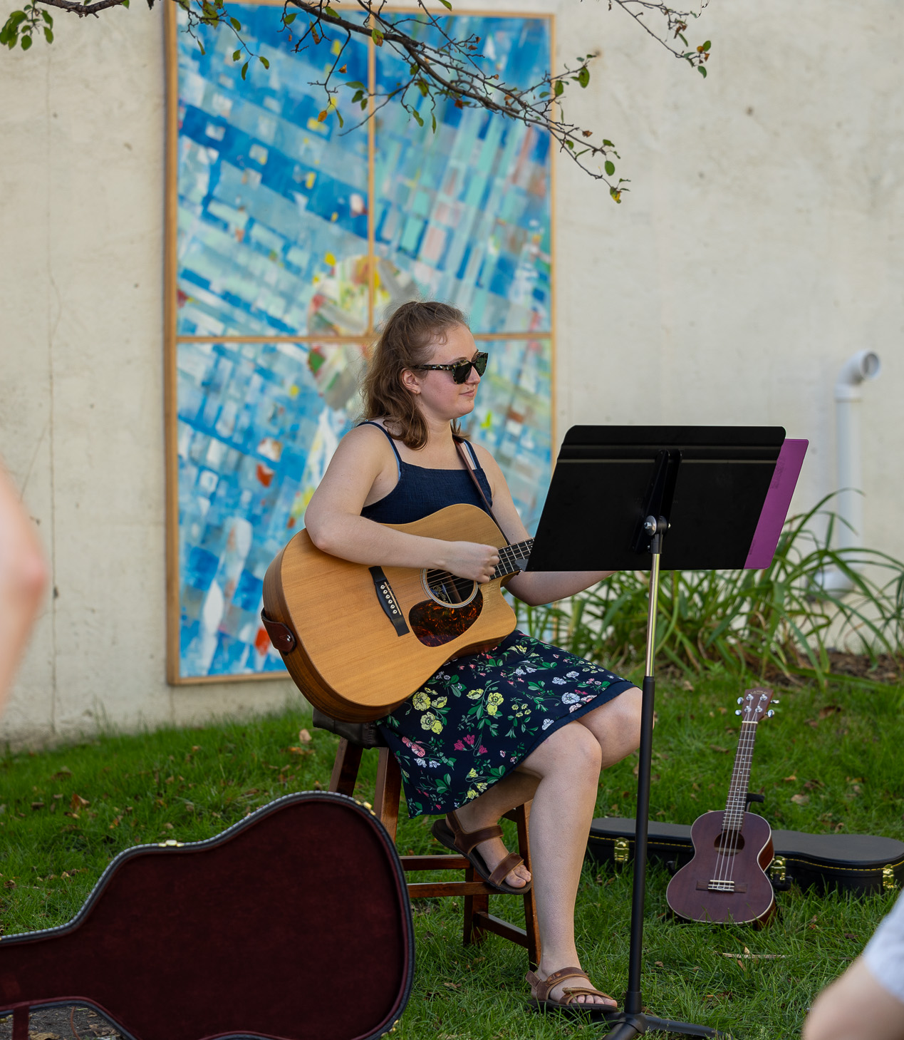 Street musician plays in downtown grand forks for folks to gather and vibe to. She is playing the string guitar with her sunnies on.