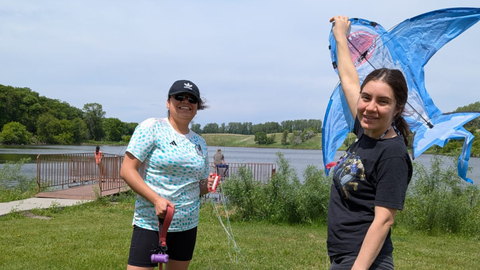 Two folks stand together at Larimore Dam with a shark kite ready to set sail in the skies!