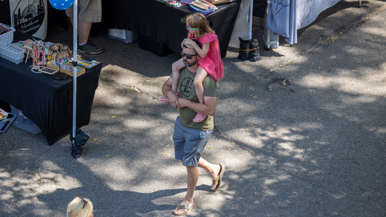Father with daughter on shoulders walking through Grand Forks Farmer's Market