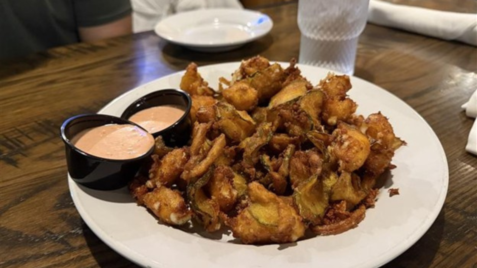 Ely's Ivy fried crispy pickles sit piled high on a small plate with two tins of spicy aoili. Yum!