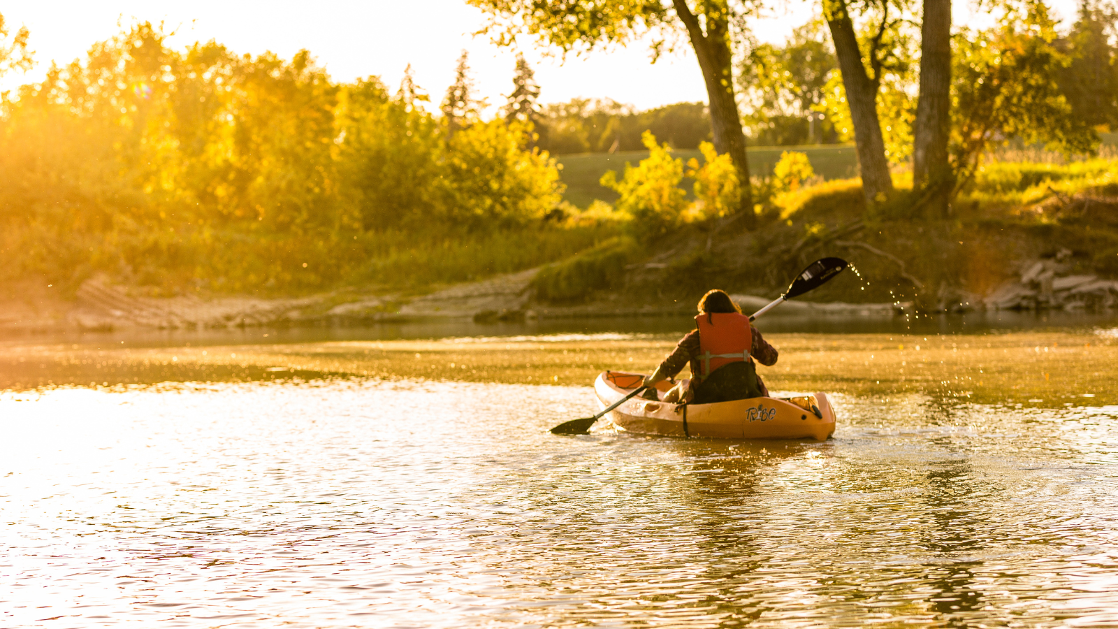 Sunset Kayaker A lone kayaker paddles toward the sunset along the Red River